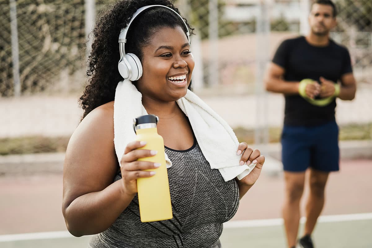 woman smiling in workout clothes outside with headphones on before medical weight loss in Mount Vernon and Marion, IL